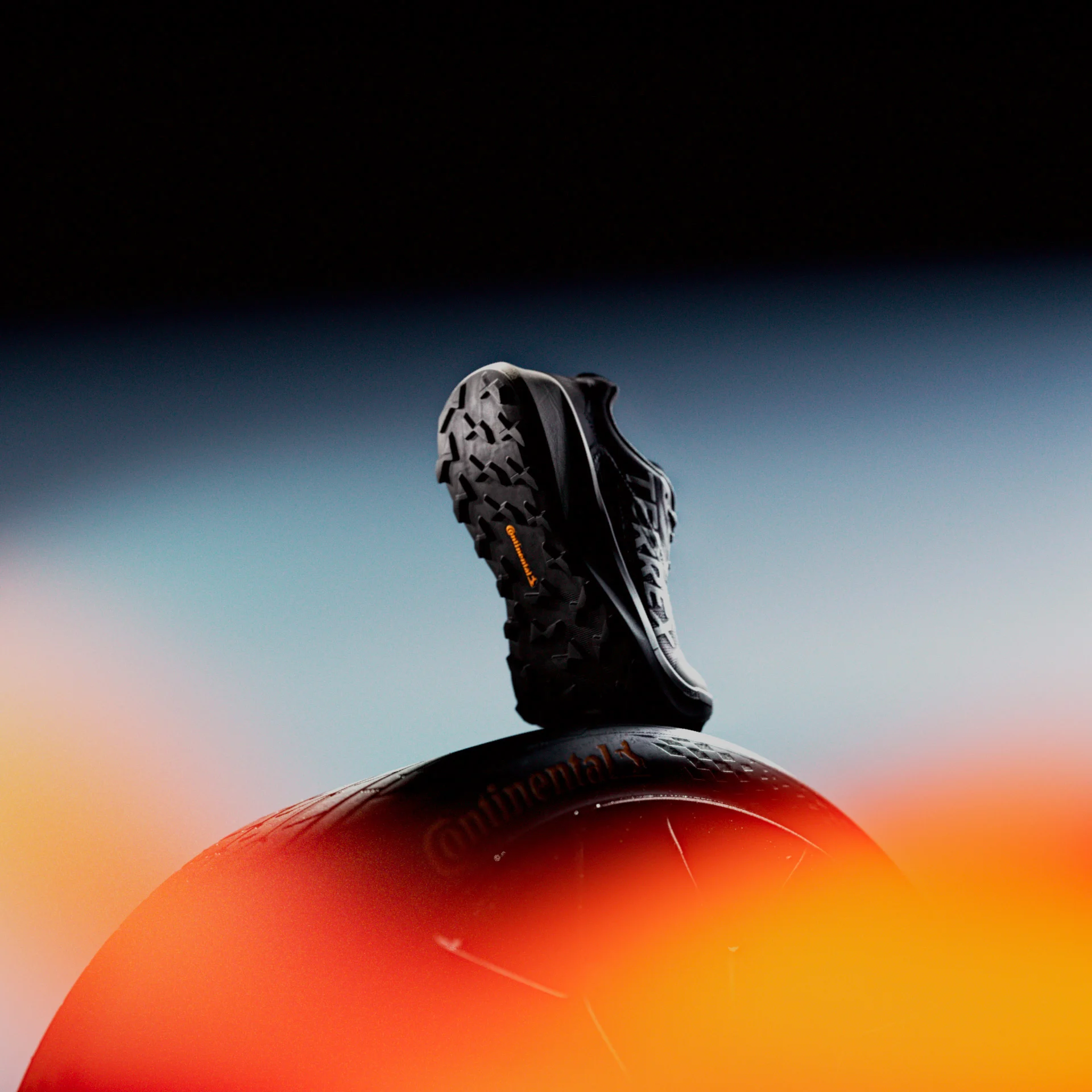 CGI product visualization of a black sports shoe on an orange sphere